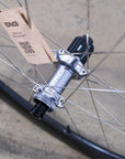 Close-up of a bicycle hub with a cardboard piece attached, on a concrete surface.
